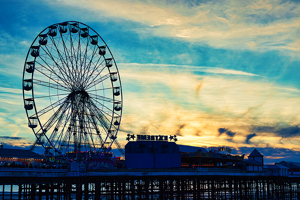 Ferris wheel silhouette against a vibrant sunset sky with clouds in Blackpool, England