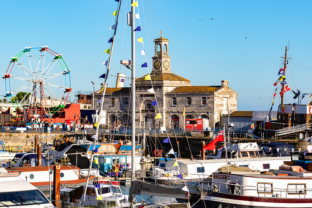 Bustling harbor with boats docked, historic building in the background, and a Ferris wheel under a clear blue sky , Hastings, East Sussex, England, United Kingdom, Europe