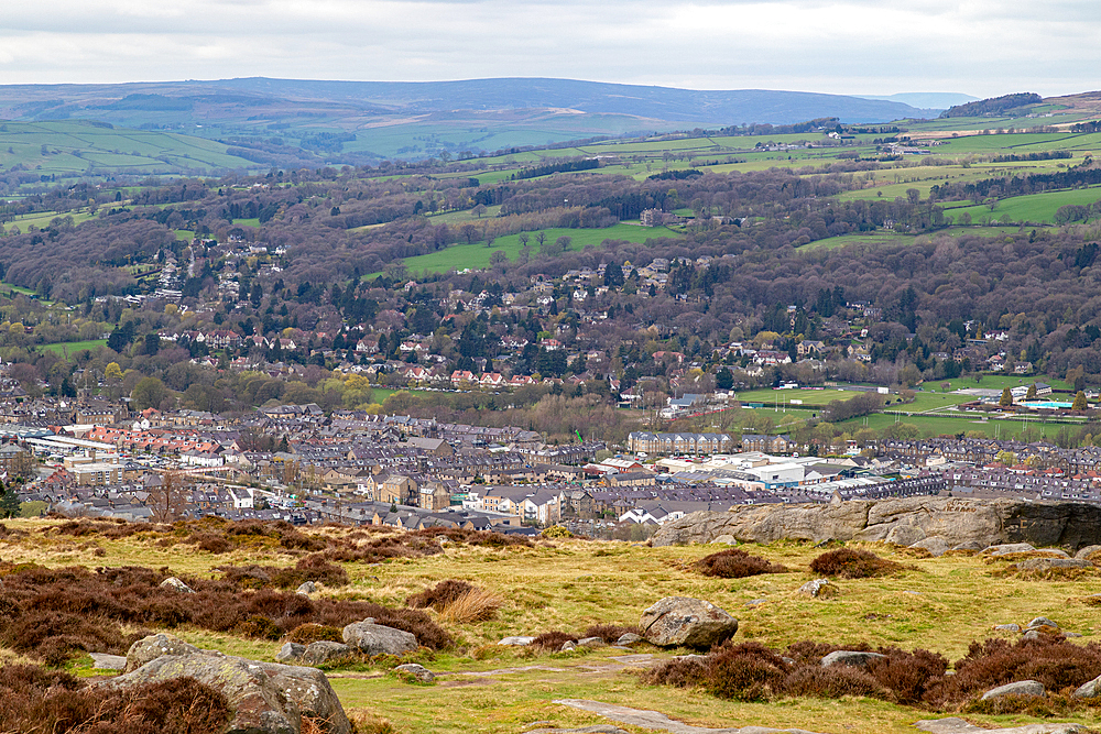 Scenic view of a quaint town nestled in a lush valley with rolling hills in the background and rocky terrain in the foreground in Ilkley, North Yorkshire, England, United Kingdom, Europe