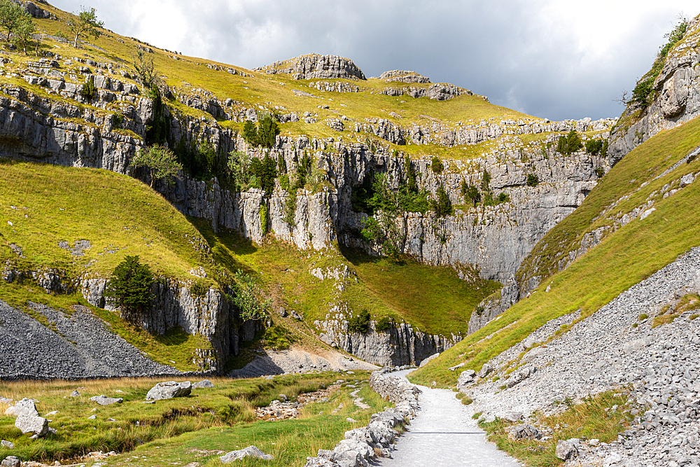 Scenic limestone valley with a gravel path leading through, under a partly cloudy sky, North Yorkshire, England, United Kingdom, Europe