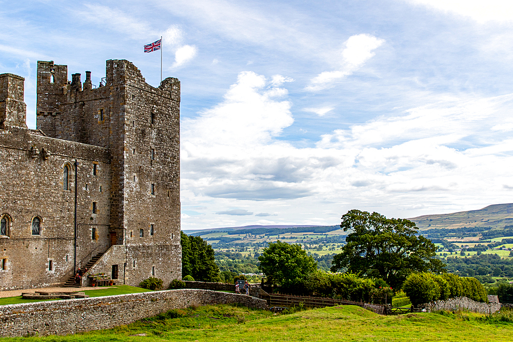 Medieval castle with a flag on a sunny day, surrounded by greenery and with a scenic view of the countryside, Bolton Castle, Yorkshire Dales, Yorkshire, England, United Kingdom, Europe