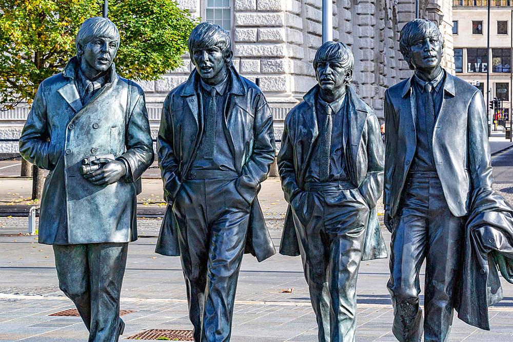 Bronze statues of the four members of a famous band, The Beatles, walking in line on a city street, with buildings in the background in Liverpool, Merseyside, England, United Kingdom, Europe