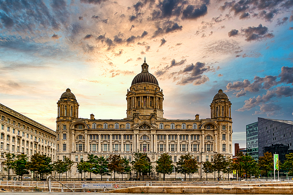 Historic building with domes against a dramatic sunset sky, flanked by trees and a water feature in Liverpool, Merseyside, England, United Kingdom, Europe