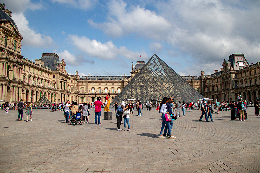 Tourists at the Louvre Museum courtyard with iconic glass pyramid and historic palace, Paris, France, Europe