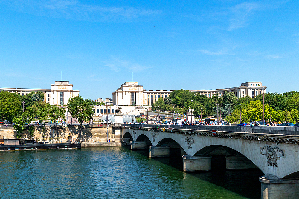 Scenic view of a historic bridge over a river with classical buildings in the background under a clear blue sky, Paris, France, Europe