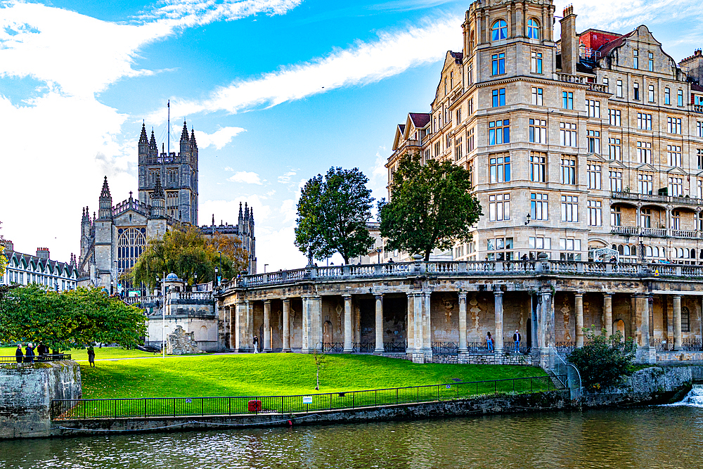 Historic cityscape with Abbey, classic architecture, and riverfront promenade under a blue sky, Bath, Somerset, England, United Kingdom, Europe