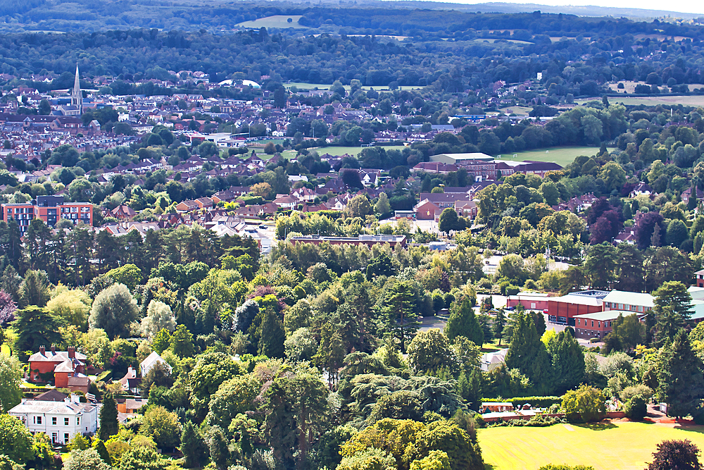 Aerial view of a lush green landscape with a mix of urban and natural areas, showcasing a town amidst forests under a clear sky, North Yorkshire, England, United Kingdom, Europe