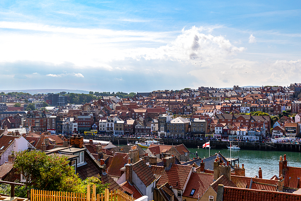 Aerial view of a coastal town with historic buildings and a harbor under a blue sky with clouds in Whitby, Yorkshire, England, United Kingdom, Europe