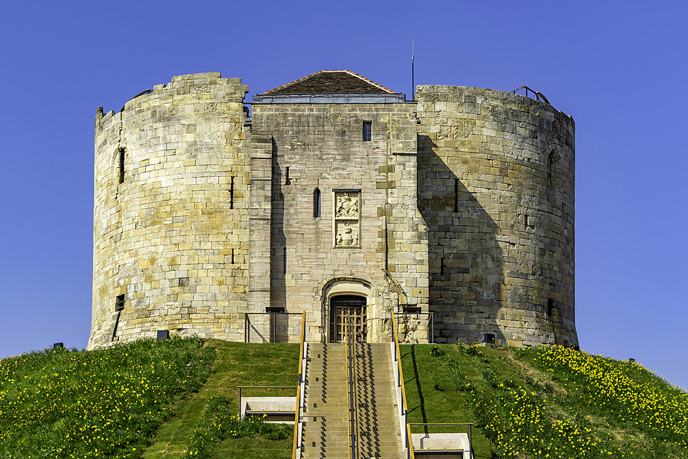 Medieval stone tower on a hill with a clear blue sky in the background, Clifford's Tower, York, North Yorkshire, England, United Kingdom, Europe