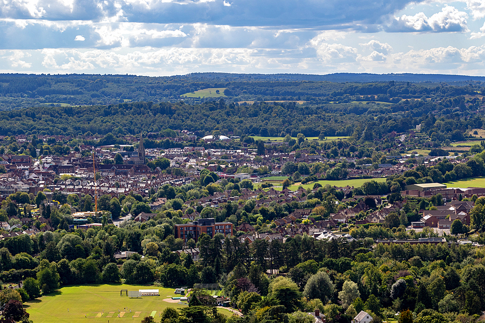 Aerial view of a lush green landscape with a town nestled among trees under a cloudy sky, Box Hill, Surrey, England, United Kingdom, Europe