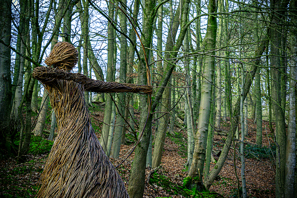 Straw sculpture of a humanoid figure in a forest, with arms outstretched amidst bare trees, Skipton, Yorkshire, England, United Kingdom, Europe