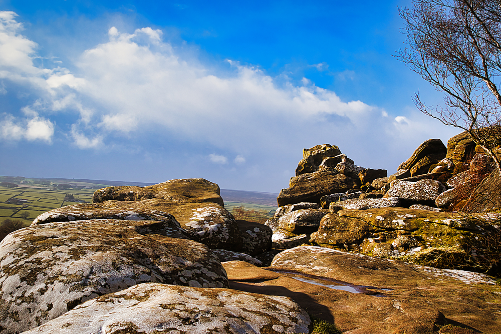 Scenic view of rugged rocks against a blue sky with fluffy clouds, highlighting the natural beauty of a mountainous landscape at Brimham Rocks, in North Yorkshire