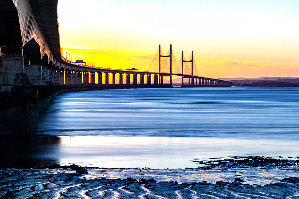 Long exposure of a serene sunset over the Prince of Wales Bridge, the Second Severn Crossing, M4 motorway over the River Severn, clear skies, and warm sunlight, between England and Wales, United Kingdom, Europe