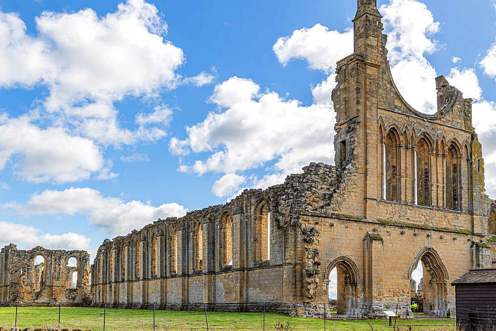 Ancient ruins of a Gothic abbey with arches under a blue sky with clouds at Byland Abbey, North Yorkshire, England, United Kingdom, Europe