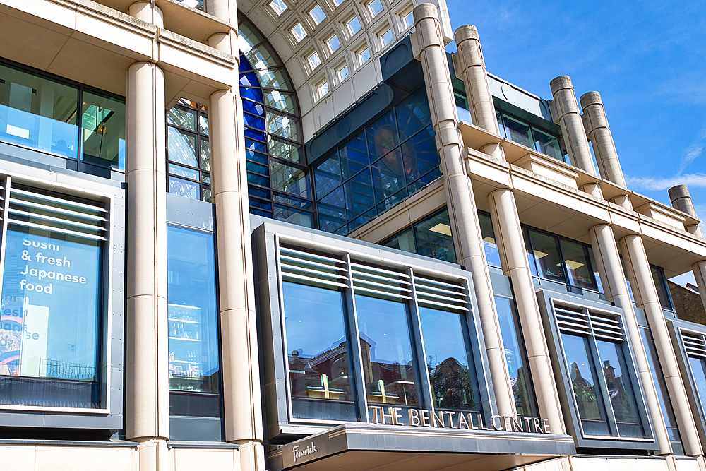 Exterior shot of The Bentall Centre building with glass windows, concrete pillars, and blue sky at Bentall Centre in Kingston, UK.