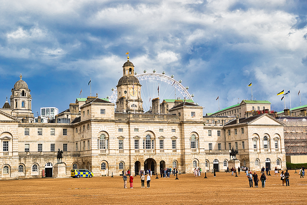 A grand, pale stone building with classical architecture dominates the frame, featuring a prominent clock tower. In the background, a large Ferris wheel is visible against a dramatic, cloudy sky.