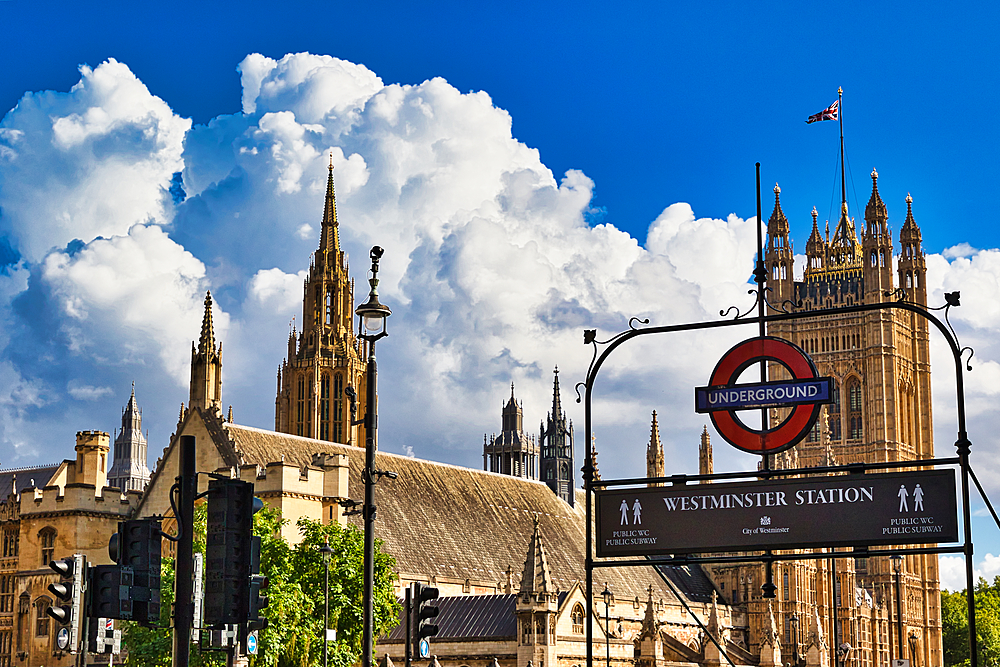 London's iconic Westminster Station, featuring the Houses of Parliament and the Union Jack against a dramatic blue sky with fluffy white clouds.