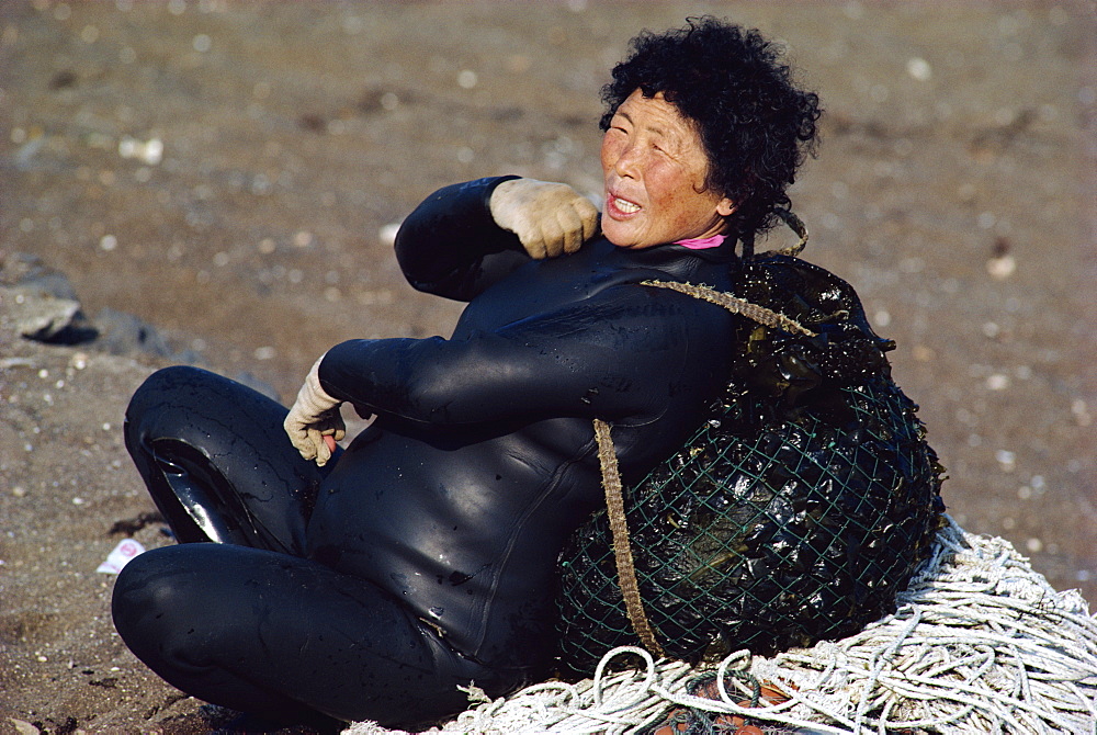 A woman diver or Haenyow with plastic float, diving for urchins, clams, shellfish and edible seaweed, on Songsan Beach on Cheju Island, South Korea, Asia 