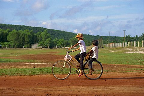 Two children riding on a bicycle through a rural area on Phu Quoc Island in south west Vietnam, Indochina, Southeast Asia, Asia