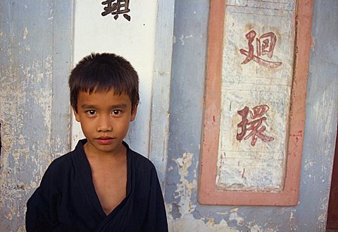 Portrait of a small boy beside Chinese characters on a wall, in Vietnam, Indochina, Southeast Asia, Asia