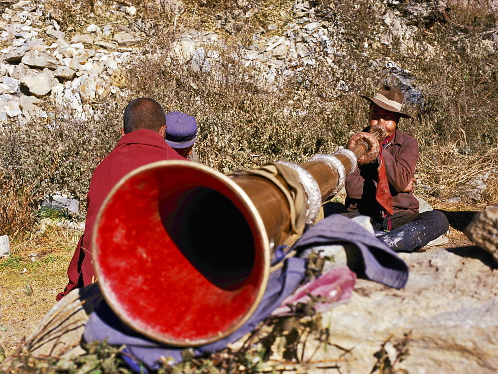 Blowing giant horn at Ganden Monastery, Tibet, China, Asia