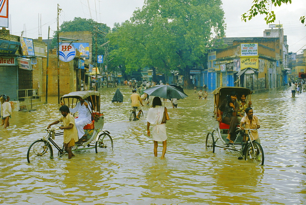 Rickshaws being pushed through the monsoon floods in a town, India