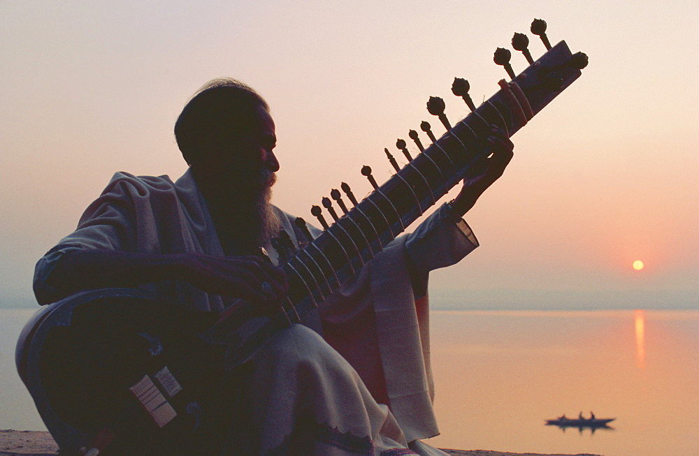 Elderly man playing the sitar beside the Ganges (Ganga) River, Varanasi (Benares), Uttar Pradesh State, India