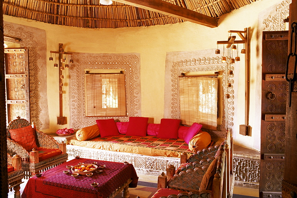 Raised mud reliefs inlaid with mirror on the walls of living area in modern home in traditional tribal Rabari round mud hut, Bunga style, near Ahmedabad, Gujarat state, India, Asia