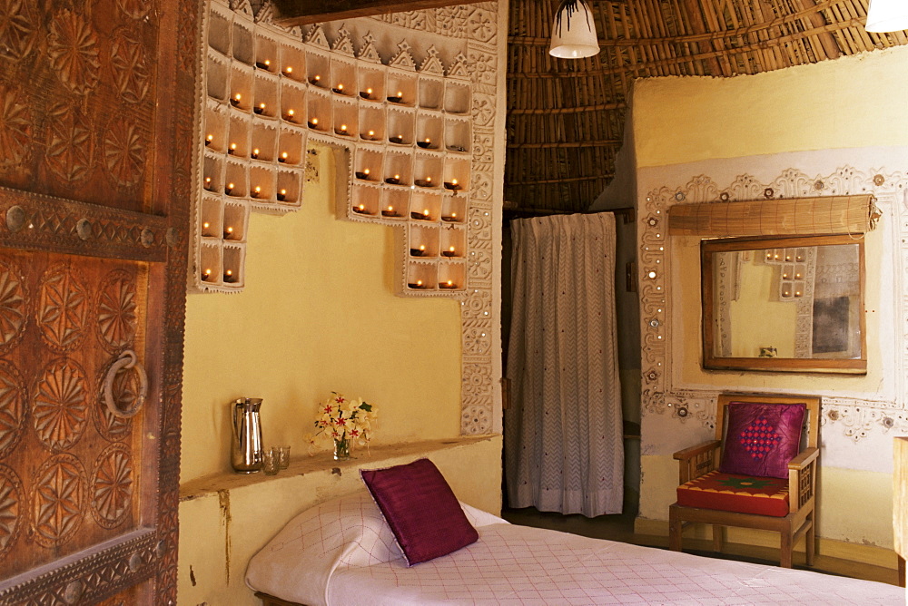 Raised mud reliefs inlaid with mirror on the walls in bedroom of modern home in traditional tribal Rabari round mud hut, Bunga style, near Ahmedabad, Gujarat state, India, Asia