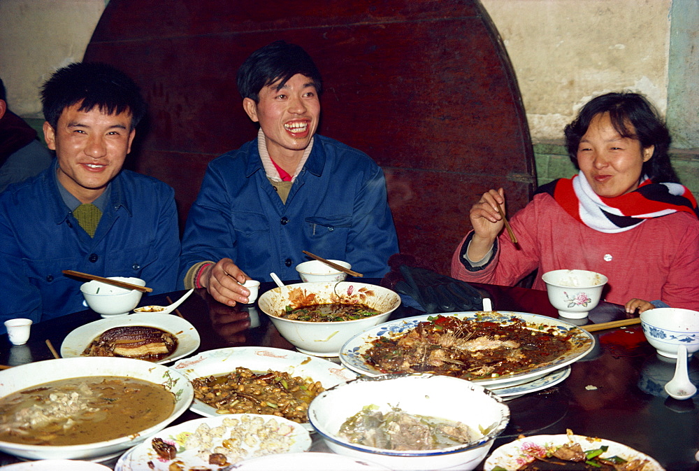 Local family with bowls of food at a banquet in Sichuan Province, China, Asia