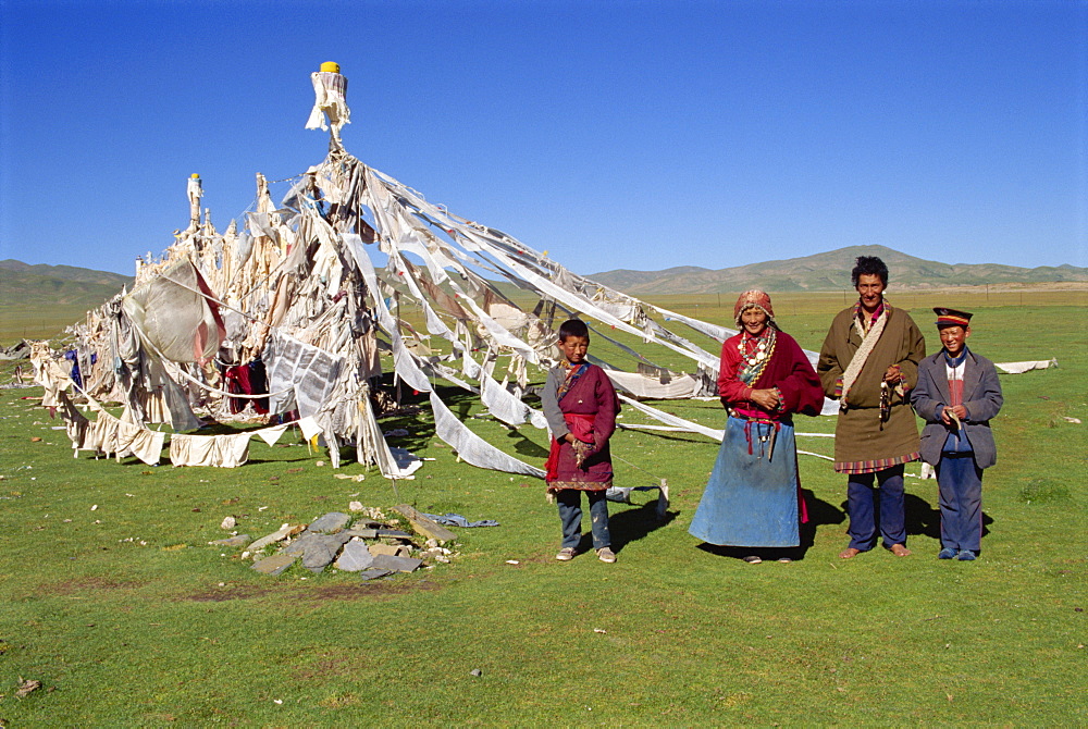 A family standing beside prayer flags at Huashixia in Qinghai, China, Asia