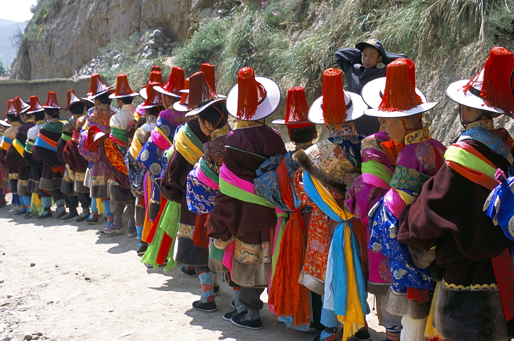 Line of people wearing Tibetan traditional dress, Tongren, Qinghai Province, China, Asia