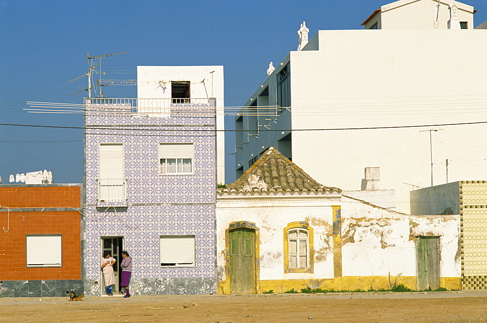 Women gossiping on the doorstep of a house on a street in small fishing village, Santa Luzia near Tavira in the Algarve, Portugal, Europe