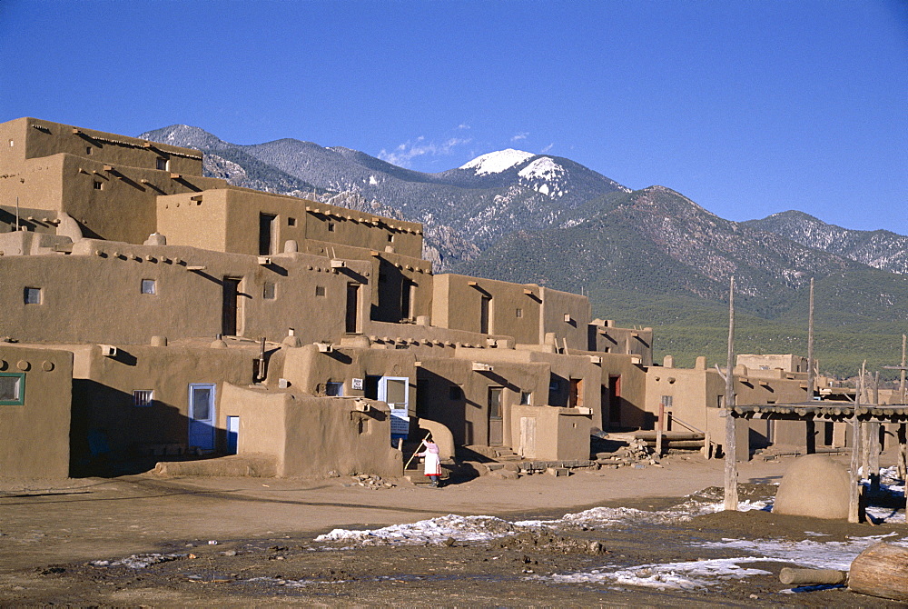 Lady sweeps up after visitors have departed, multistorey adobe buildings in north complex dating from around 1450 AD, Taos Pueblo, UNESCO World Heritage Site, Taos, New Mexico, United States of America (U.S.A.), North America