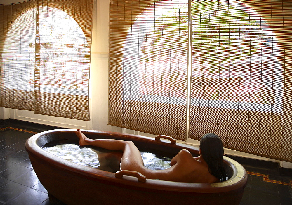 Girl inside the wooden bathtub at the Spa at Kalari Kovilakom, Kerala, India, Asia