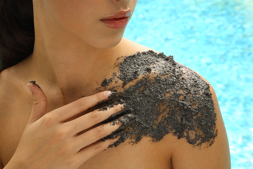 Applying sesame scrub treatment by the pool
