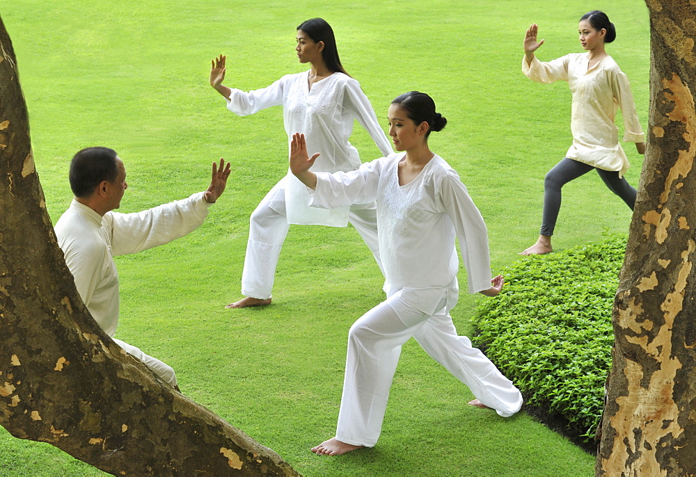 A group of people doing Tai Chi outdoors