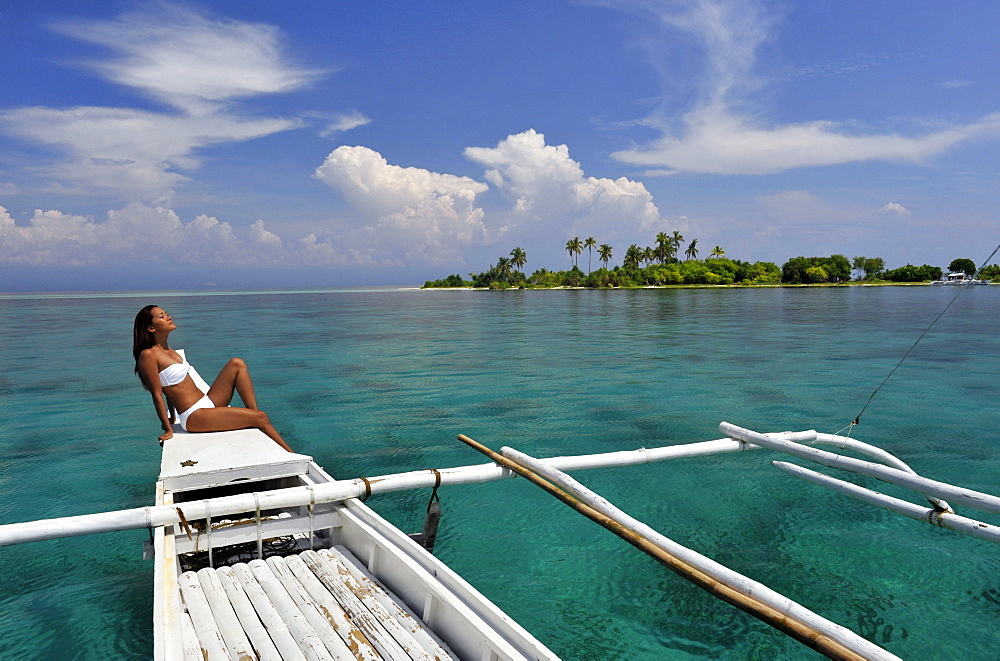 Girl on a traditional boat and the islet off the coast of Bohol, Philippines, Southeast Asia, Asia