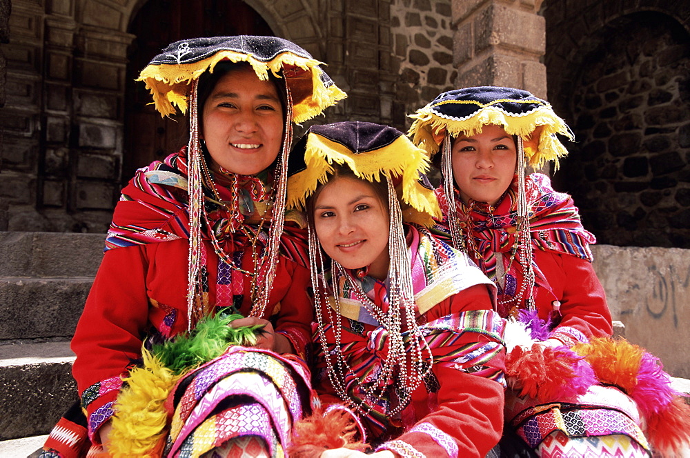 Portrait of three smiling Peruvian girls in traditional dance dress, looking at the camera, Cuzco, Peru, South America