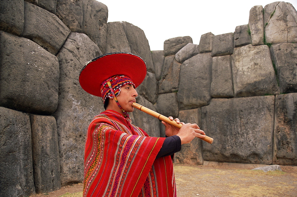 Portrait of a Peruvian man playing a flute, Inca ruins of Sacsayhuaman, near Cuzco, Peru, South America