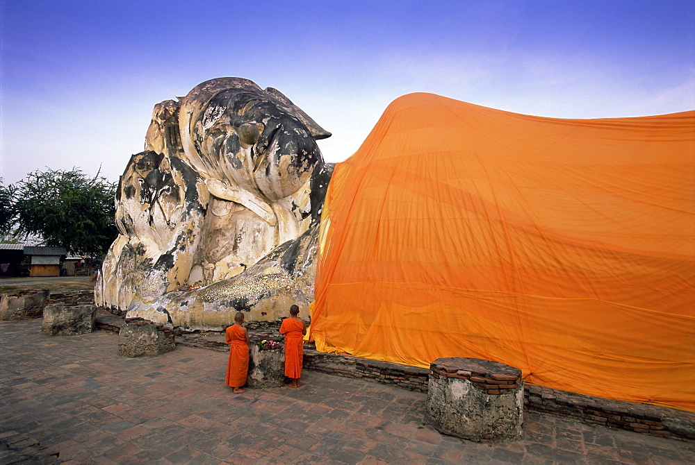 Two novice Buddhist monks in front of a statue of the reclining Budha, Wat Lokayasutharam, Ayuthaya Historical Park, Ayuthaya (Ayutthaya), UNESCO World Heritage Site, central Thailand, Thailand, Southeast Asia, Asia