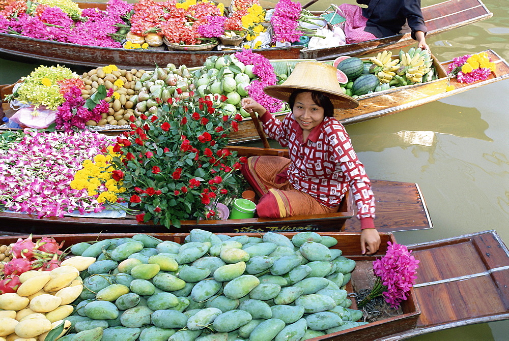 Market trader in boat selling flowers and fruit, Damnoen Saduak floating market, Bangkok, Thailand, Southeast Asia, Asia