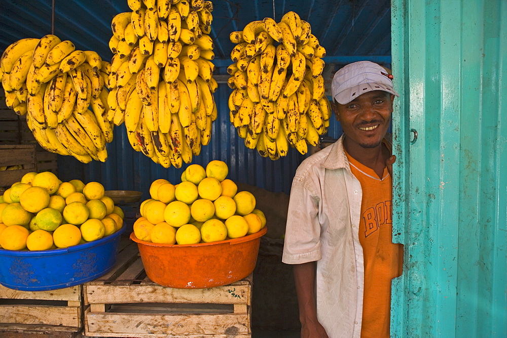 man standing next to Bananas in a market stall in Gonder, Gonder, Ethiopia, Africa