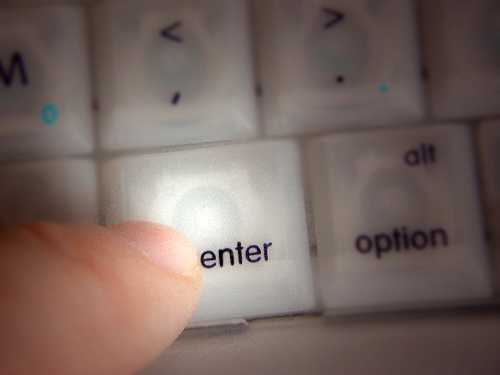 Finger pressing Enter key on a computer keyboard