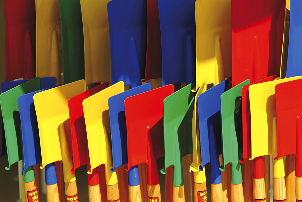 Multi coloured spades on sale at a beach shop on the Planche, Deauville, Calvados, Normandy, France, Europe