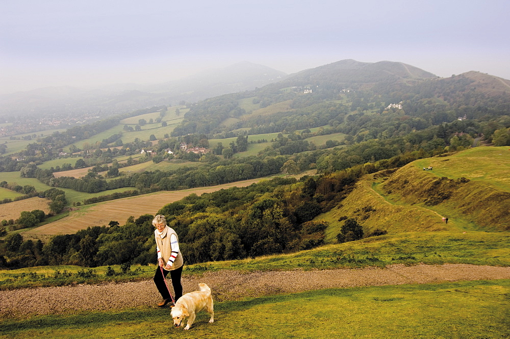 Woman taking dog for a walk, British Camp, Hereford Beacon, Malvern Hills, Herefordshire, Midlands, England, United Kingdom, Europe