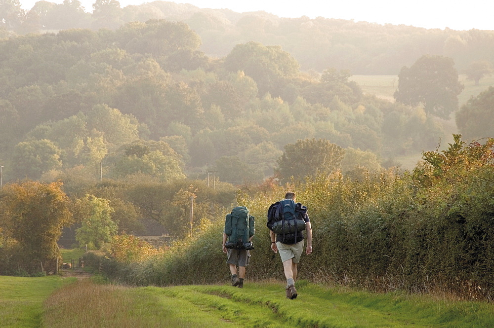 Two walkers with rucksacks on the Cotswold Way footpath, Stanway village, The Cotswolds, Gloucestershire, England, United Kingdom, Europe