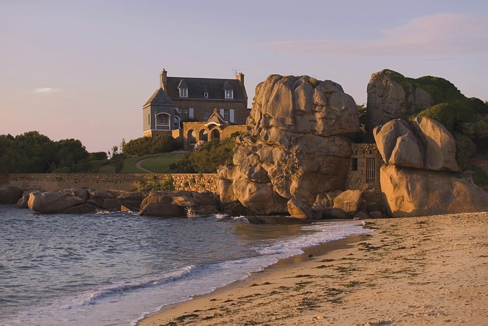 Beach house built behind rocks, Tregastel, Cote de Granit Rose, Cotes d'Armor, Brittany, France, Europe