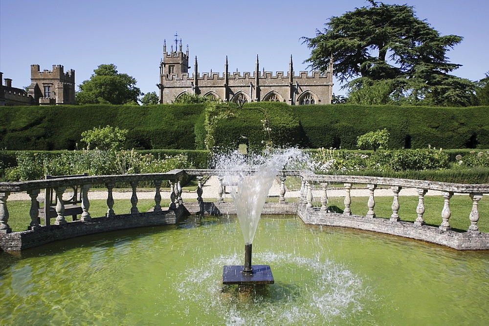 Fountain in the Queens Garden and church beyond, Sudeley castle, Winchcombe village, the Cotswolds, Gloucestershire, England, United Kingdom, Europe