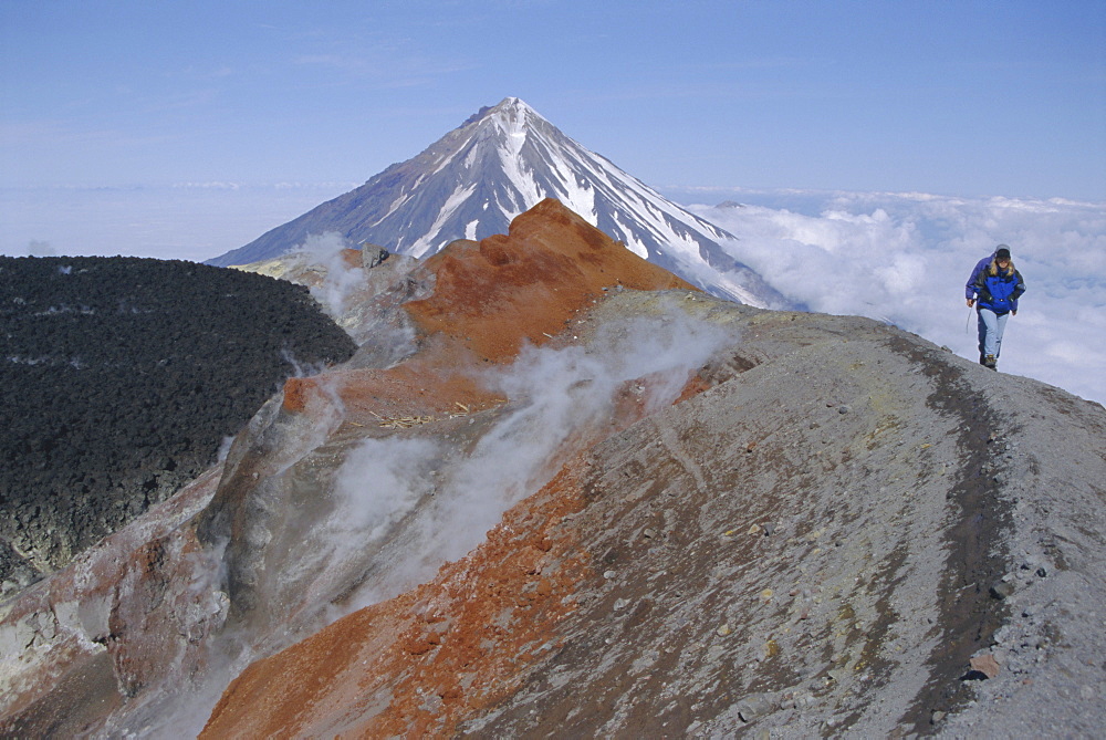 Koryaksky volcano seen beyond walkers on crater rim of Avacha volcano, Kamchatka, East Siberia, Russia